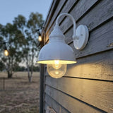 Outdoor wall light fixture on a wooden house exterior with a blurred natural background